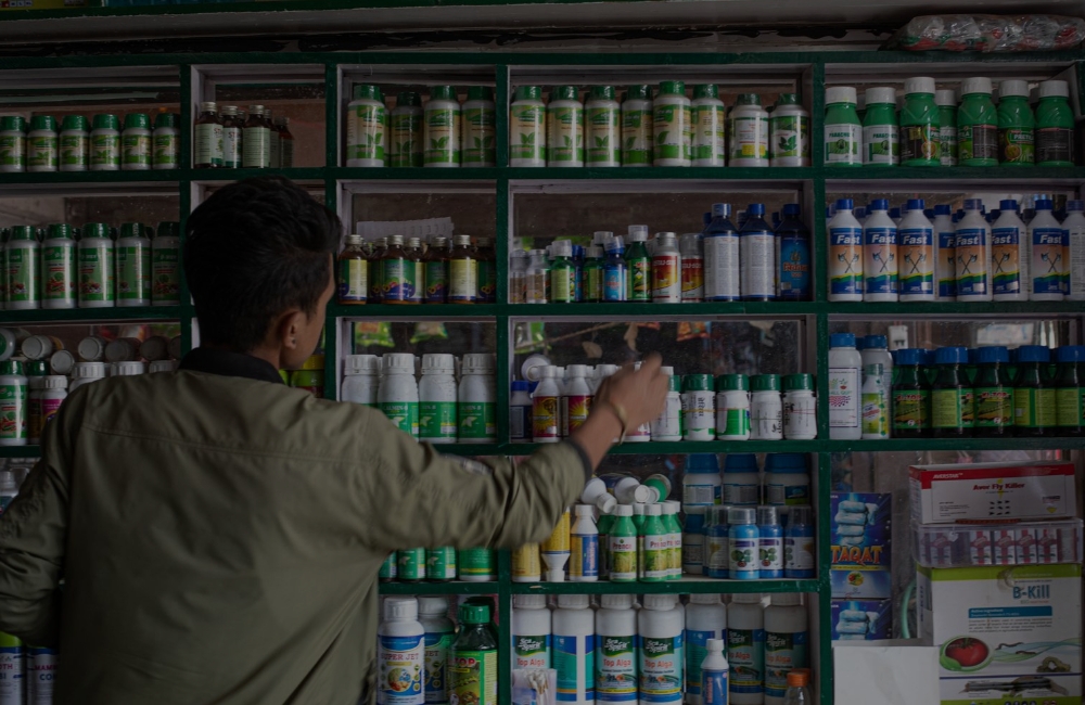 Man reaching for a bottle from shelves of pesticide bottles